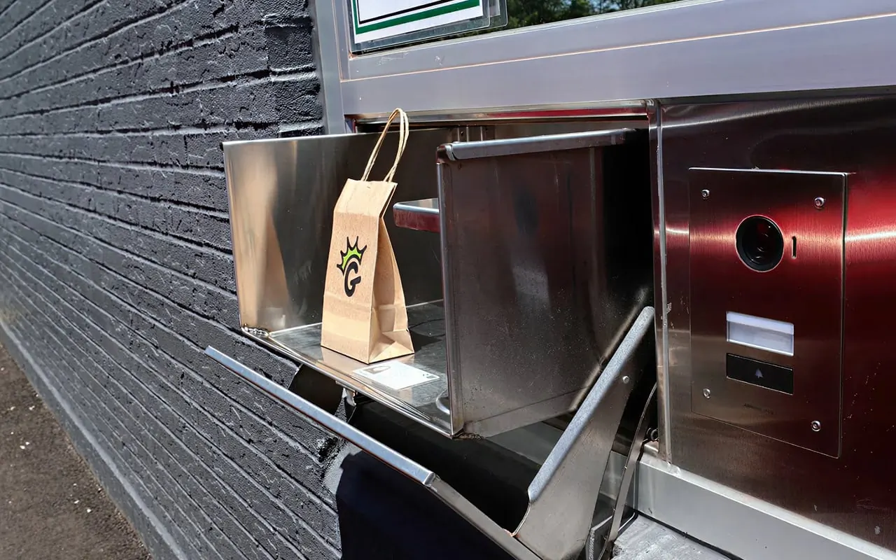 An order in a Garden paper bag sitting in the steel pass-through drawer at the drive-thru